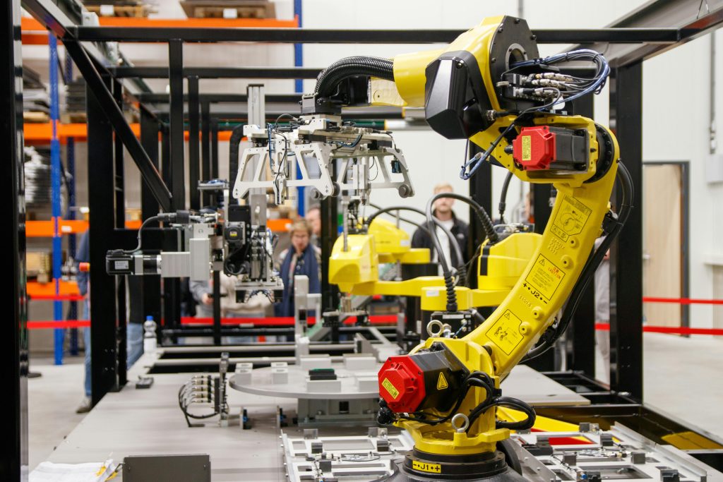 Close-up of a yellow industrial robotic arm in action at a modern manufacturing facility.
